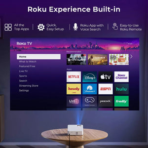 White smart projector displaying Roku TV home menu on screen.